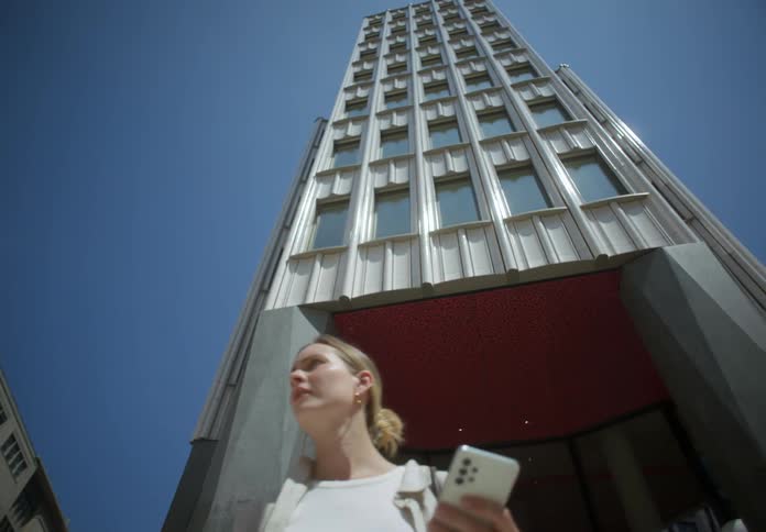 Blonde woman worried pacing back and forth outdoors holding her phone in her hand