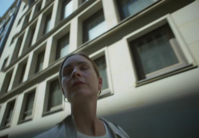 A woman walks briskly along a street lined with tall buildings