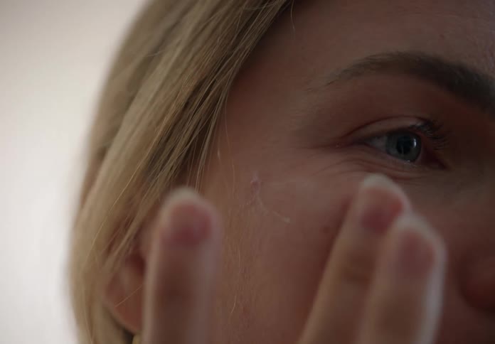 A woman puts moisturizer on her face