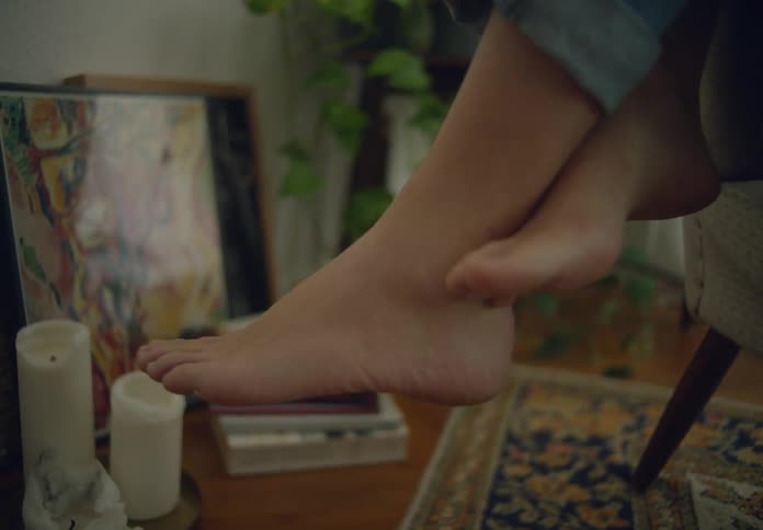 A persons bare feet hang from the chair