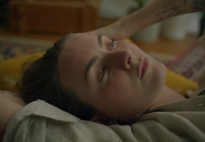 A woman lies on her back on the couch