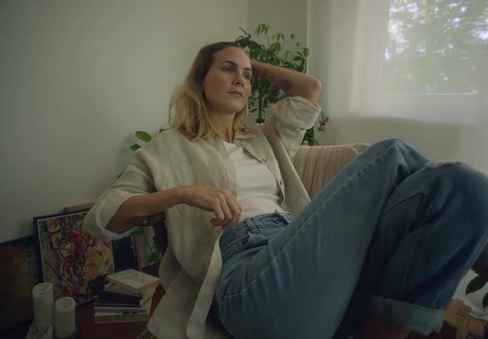 A woman sits comfortably and relaxing in a chair while indoors