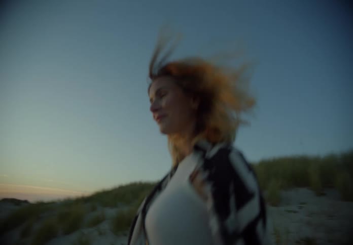 A woman walks downhill on the sand