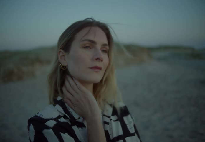 A woman is rubbing her neck on the beach