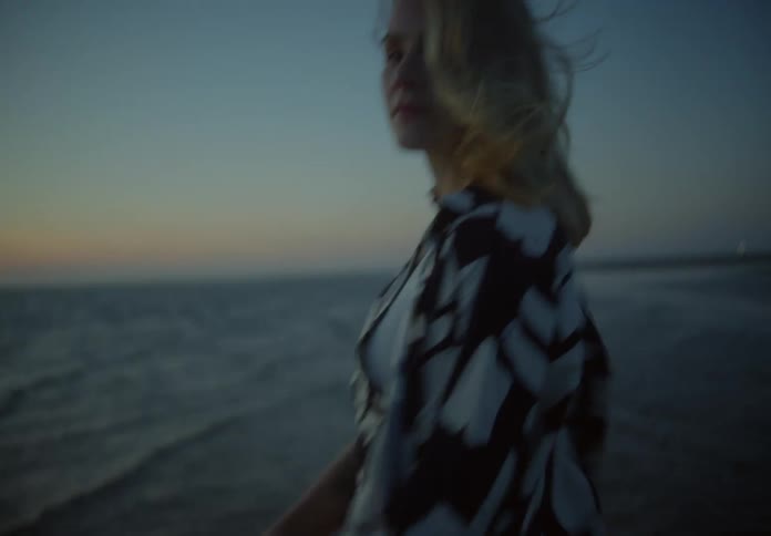 A woman stands in ankledeep water at the beach in this portrait