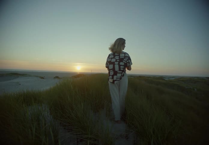 A woman is standing on the windy beach