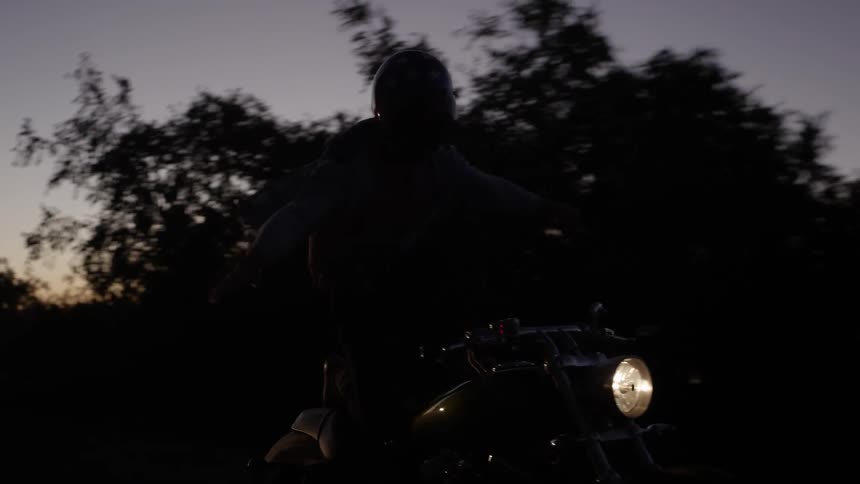 People riding standing up on motorcycles after sunset