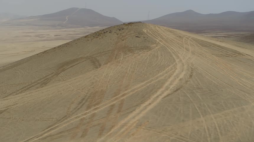Tire tracks stretch across the desert and over the mountains