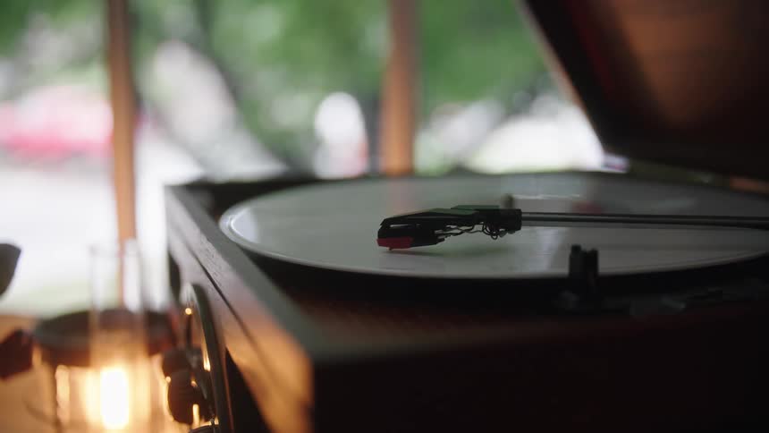 The needle of a phonograph gently sits on a vinyl record as it spins on the turntable