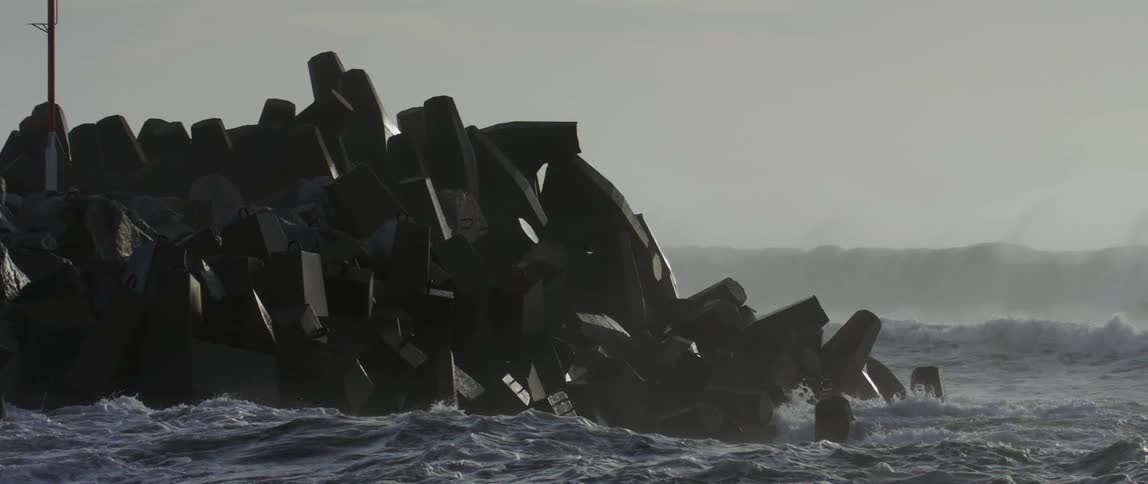 The camera captures slow motion footage of waves washing against the coastline