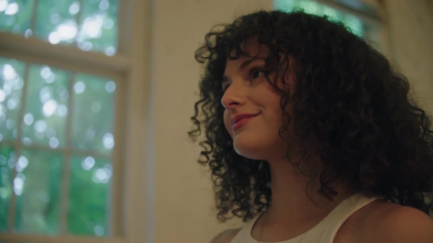 A woman looks at a painting and smiles