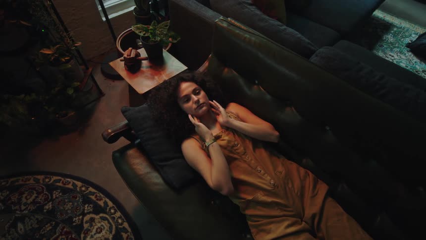 A young woman reclines on a couch as she tries to rest and relax