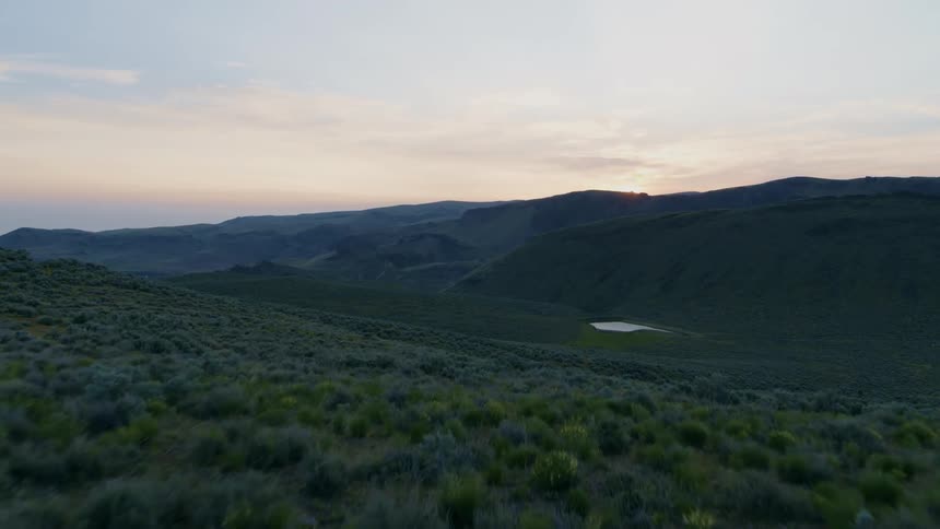 Reveal of a lush emerald green mountain valley in early dawn light