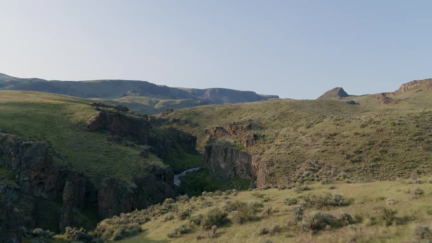 Slow descent along a sage brush slope that leads to the sheer walls of a rugged gorge