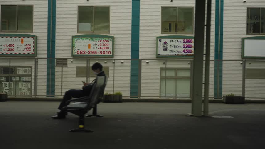 The camera moves past a platform that has seats for waiting riders
