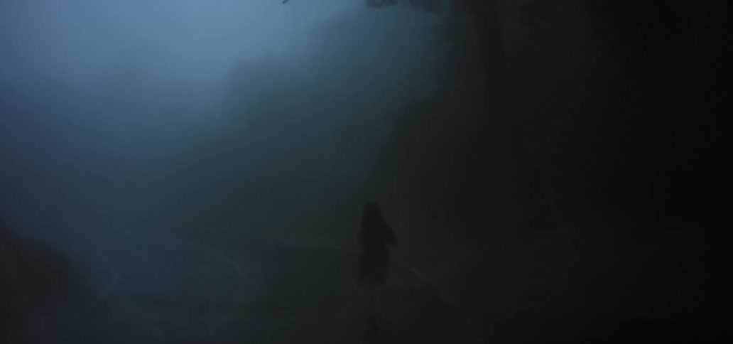 Woman silhouetted in dense fog runs toward horizon