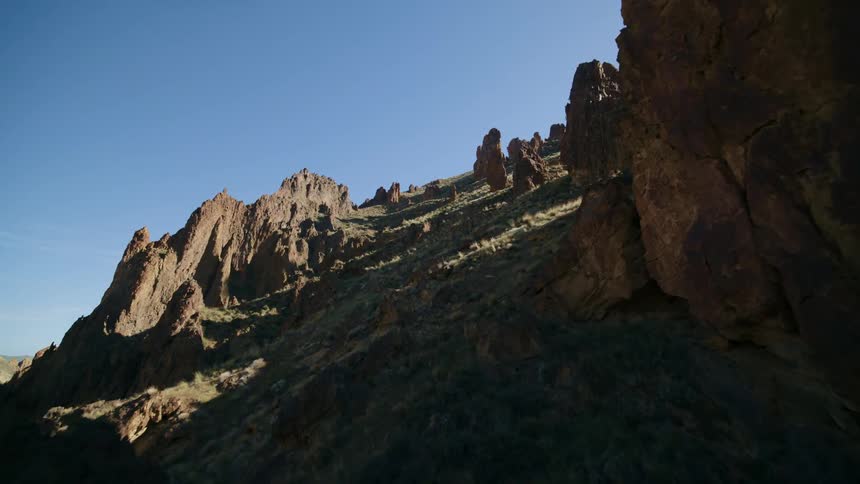 Ascending through rock pillars on a steep mountainside as the sun casts long shadows along the terrain