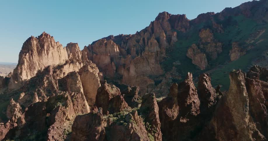 Slow approach just over the tops of jagged rock spires in a stunning sun kissed canyon