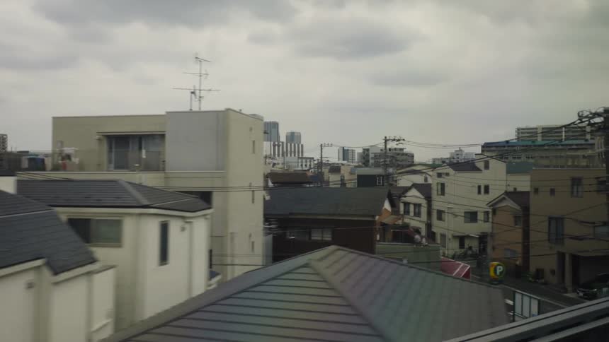 A sprawling city can be seen from the window of a moving train car