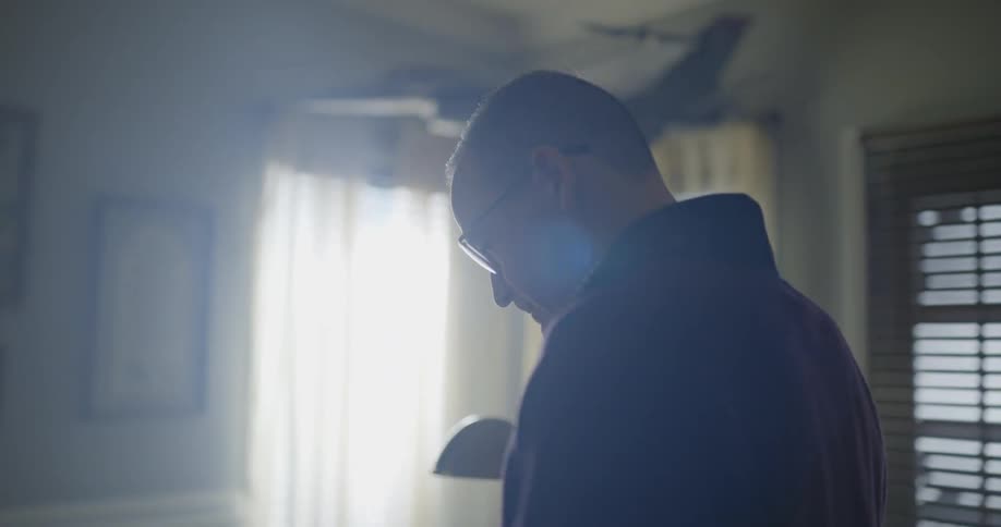 A man slowly walks through his house towards a dining table