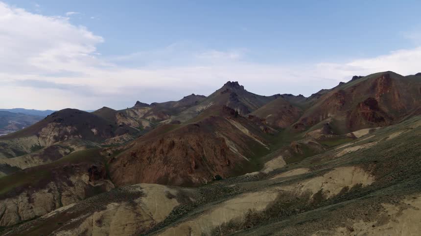 Green and tan rolling hills lead to red rock mountains