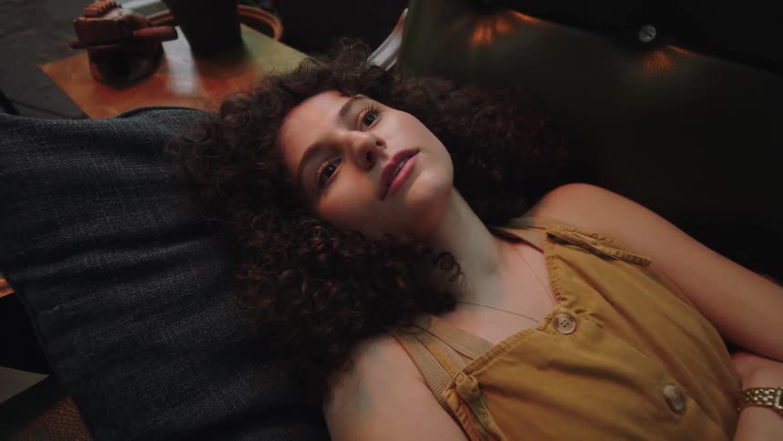 A young woman lays on a couch while looking up at the ceiling
