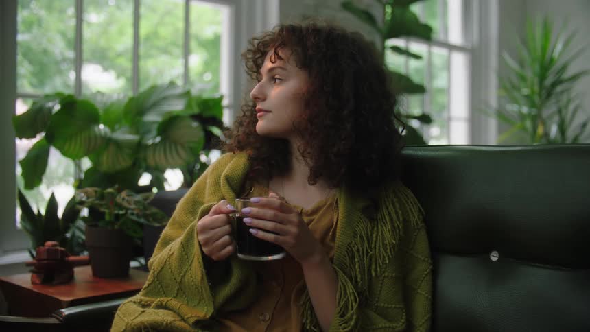 A woman has a drink on the couch