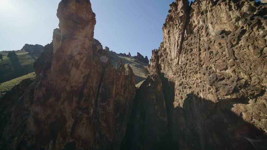 Flying between rock spires and rock formations along beautifully contoured sun kissed hills