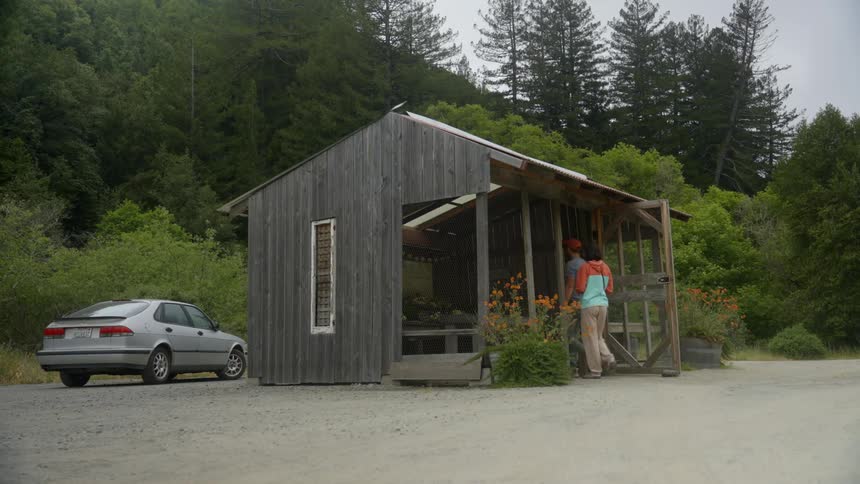 Man and a woman walking outdoors and entering a wooden flower shop