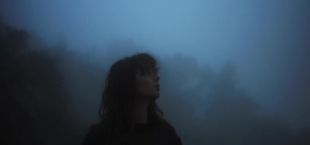 Woman standing outdoors in the fog looks around before walking away