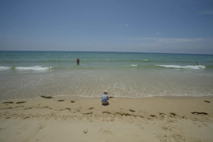 A kid having fun in the sandy beach by the sea on a sunny day