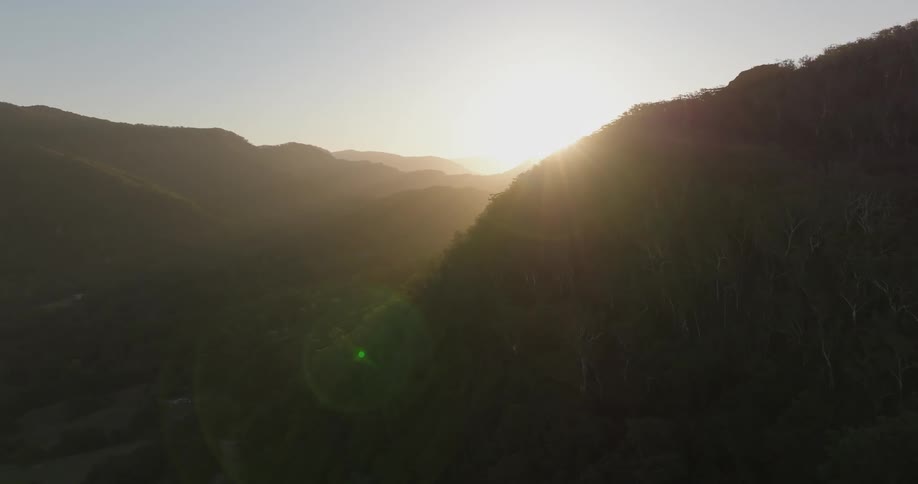 The sun is set low in the sky as it shines above a mountain range