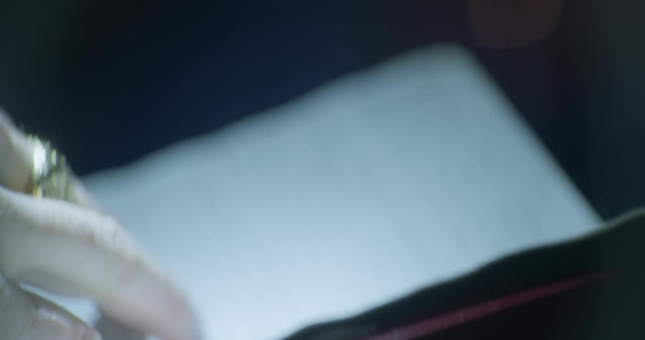 A person wearing a ring turns pages in a small notebook