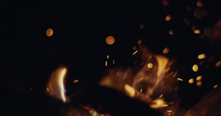 In a dark room fire is burning a piece of wood