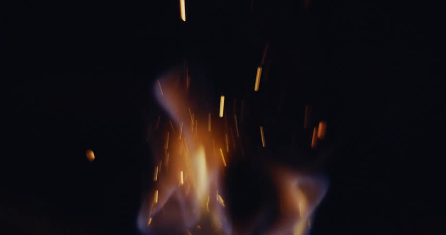 Close up of a flame burning emitting sparks into the night air