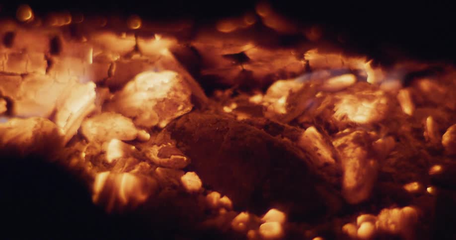 Small flames burn and release sparks while burning pieces of wood