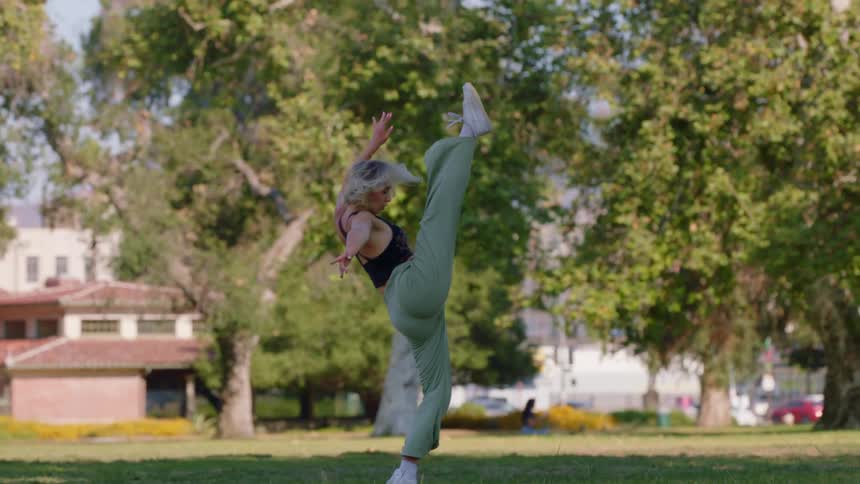 A flexible female dancer performs a high kick and bends backwards