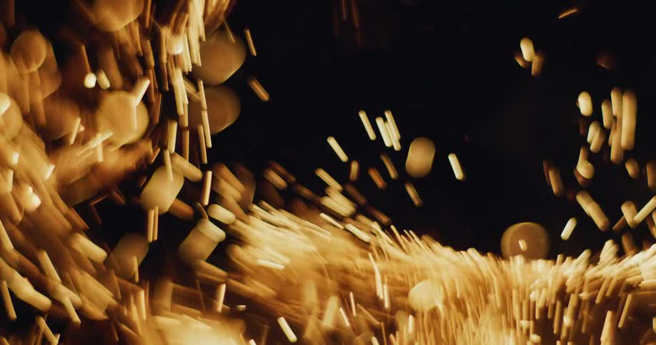 A large number of sparks are released from a burning fire at night
