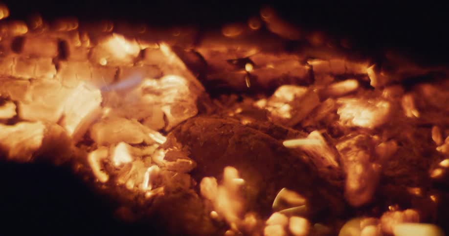 Sparks and embers are released from a piece of wood thats burning in a fire