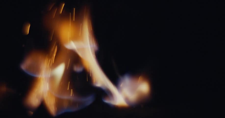 Flames dance and flicker as a small fire burns in the dark of night