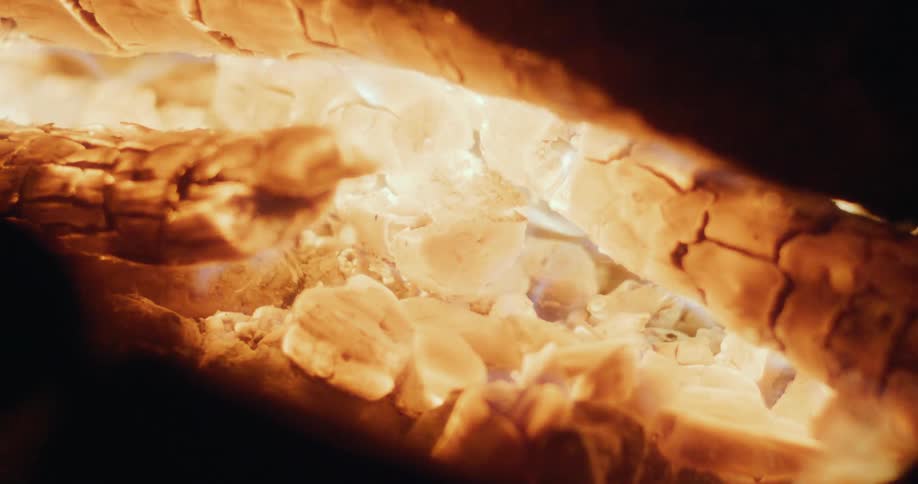The camera captures a closeup of a fire burning a pieces of wood