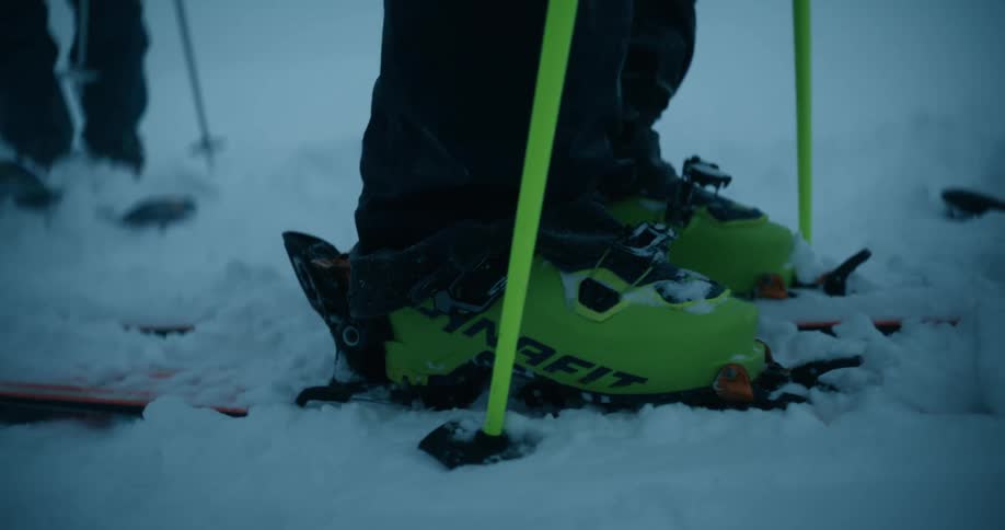 A group of men are in the snow fully kitted in skiing clothing as they prepare to ski