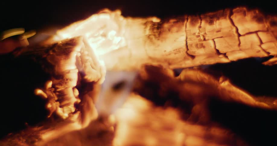 Bright yellow flames burning wood embers on a campfire