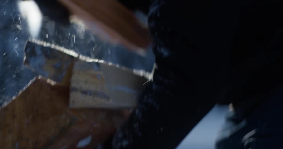 A person gathers chopped wood in their arms outdoors on a snowy day