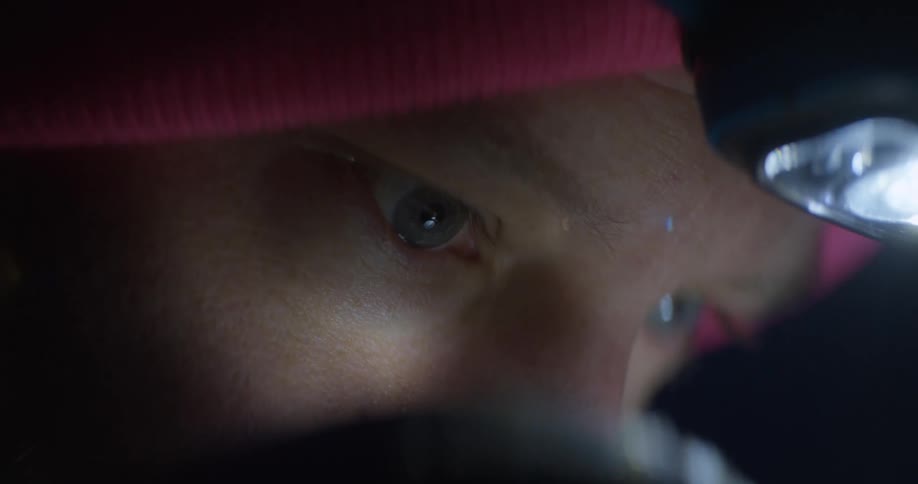 A man wearing a hat with flashlight attached during the night time