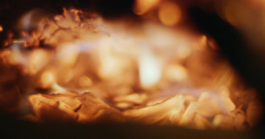 A fire burns and consumes a piece of wood while releasing embers