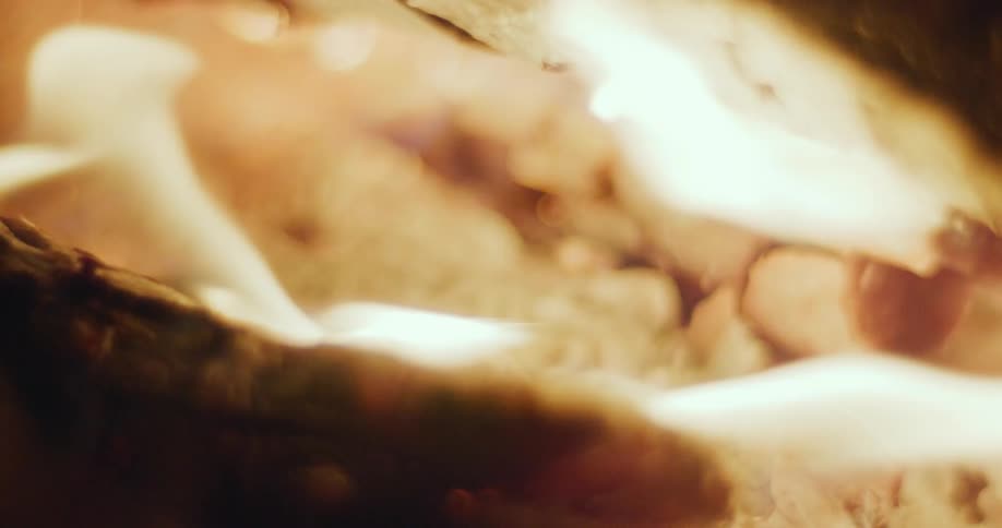 A fire is burning in between pieces of chopped wood