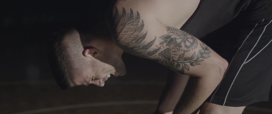 A man breathes hard and grimaces as he bends over