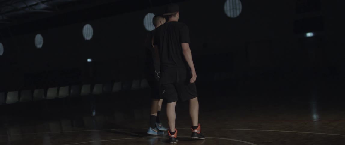 Two men get up from a basketball court floor and start to play