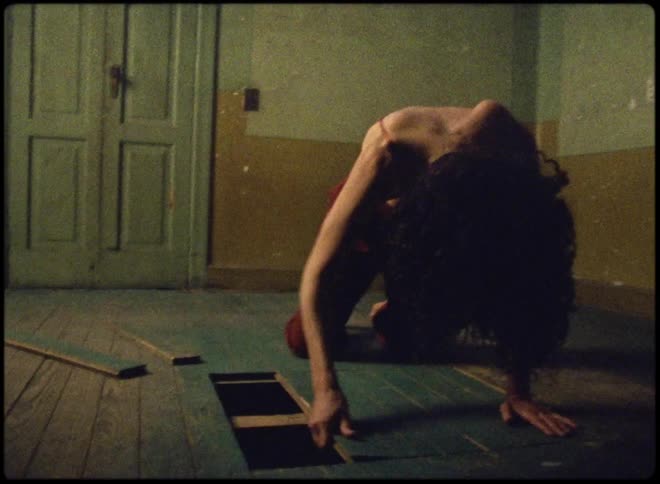A woman on her hands and knees rapidly pulls up boards from the floor
